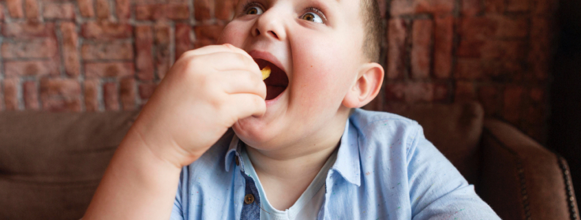 Obesità infantile, un ragazzino in sovrappeso mangia patatine