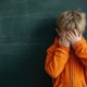 dsa un bambino alla lavagna si copre il volto con le mani in segno di vergogna