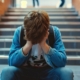 gogna social, un giovane con aria affrantra siede sulle scale della scuola