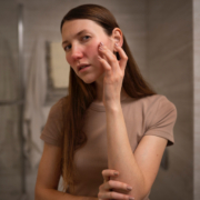 una donna controlla la pelle del viso allo specchio