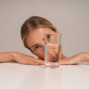 calcoli renali, una donna guarda attraverso un bicchiere d'acqua