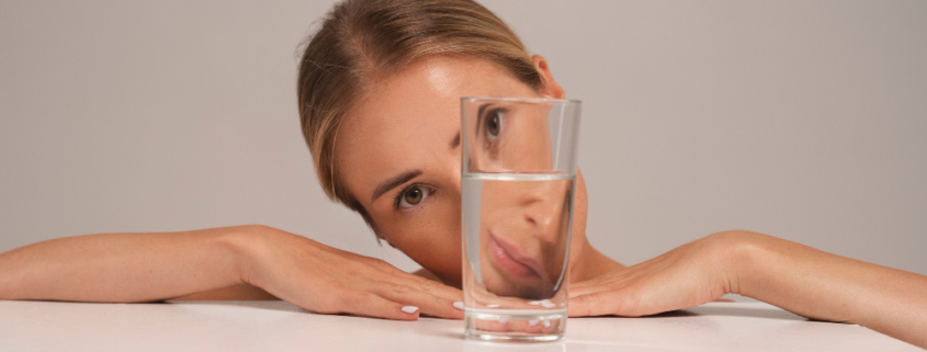 calcoli renali, una donna guarda attraverso un bicchiere d'acqua