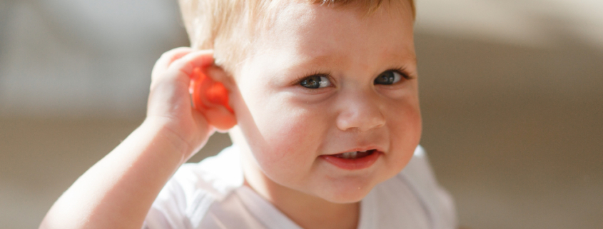 impianto cocleare, un bambino con la mano all'orecchio